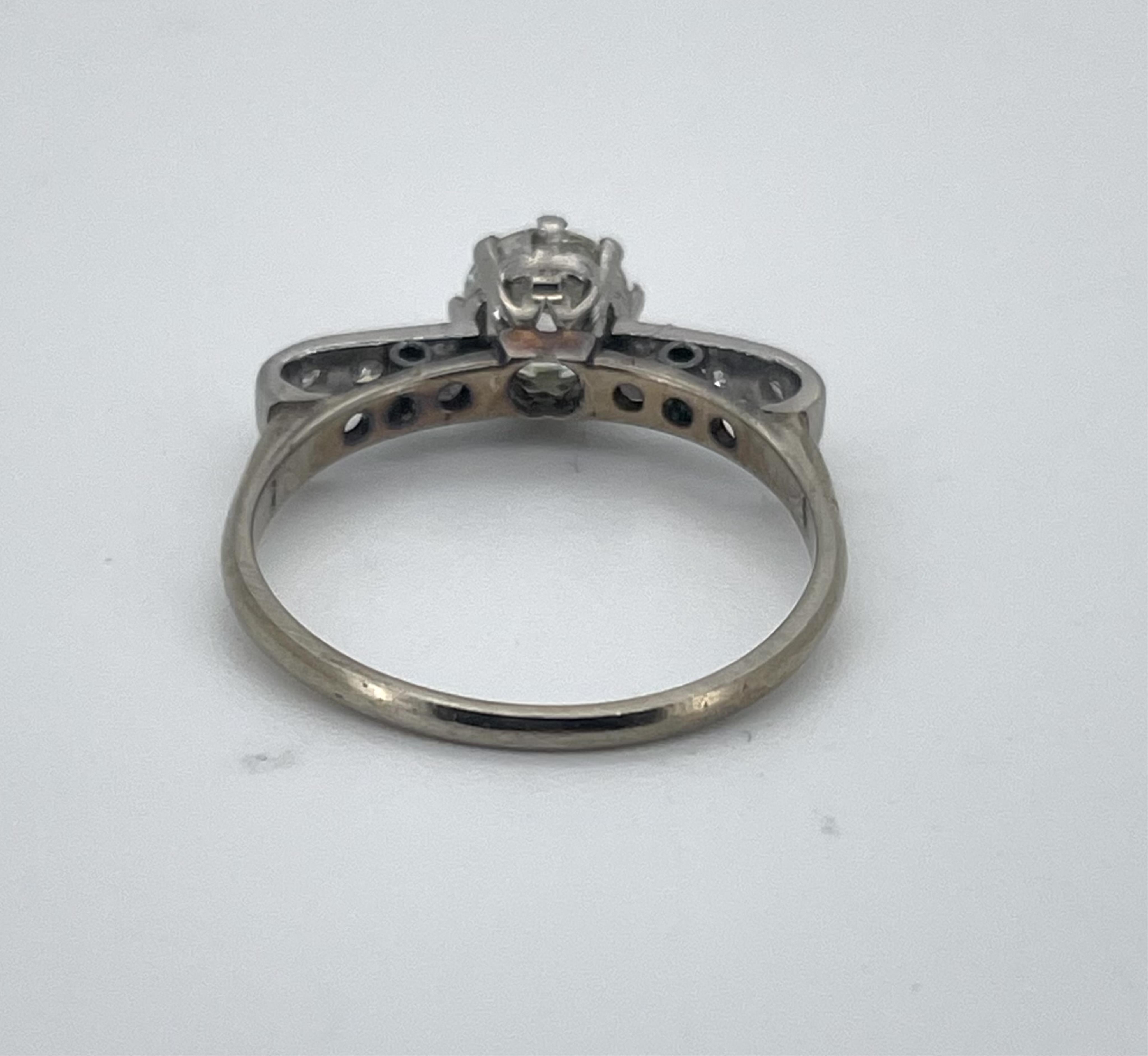 A white metal, stamped 18ct & plat. and single stone diamond ring, with six stone diamond chip set shoulders, the stone diameter approx. 5.5mm, with a depth of 3.4mm, size N.